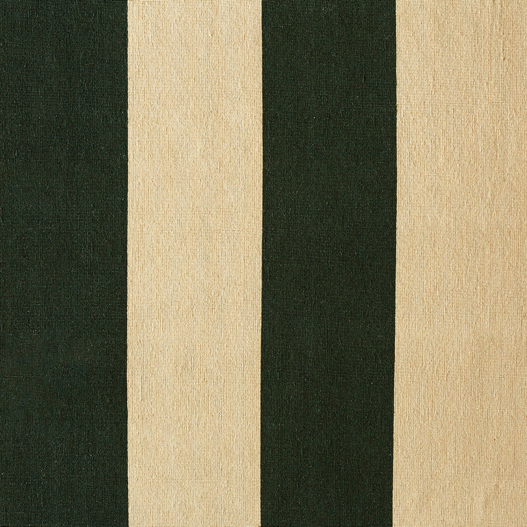 A large white and green handmade flatweave rug sitting under a dining room table laid for lunch, next to some hanging plants