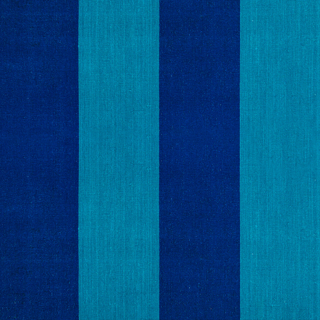 A sky blue and mid blue large striped wool rug in a living room with a sofa and bi-fold doors. This comes from a range of wooll rugs and runners which includes striped, flatweave and heavyweight styles made from ethically sourced New Zealand wool. Sizes include kitchen rugs, small bedroom rugs and long hallway runners