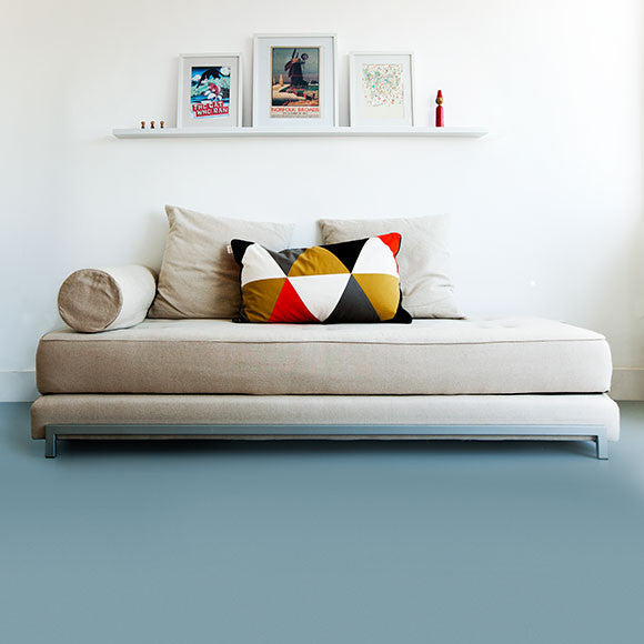 A shot of modern light blue vinyl flooring in a room with a day bed and pictures on the wall